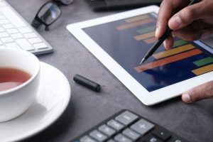 Main pointant au stylet un graphique en barres sur une tablette, illustrant l'analyse des données par l'IA dans Odoo 20