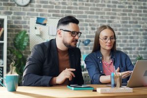 Un homme et une femme travaillant ensemble sur un ordinateur portable, illustrant la prise en main d'Odoo 20 au quotidien