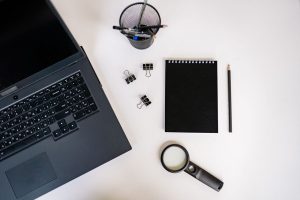 Ordinateur portable, carnet et loupe sur un bureau, symbole de la relecture du code généré par IA