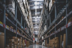 Allée d'entrepôt bordée de rayonnages chargés de cartons, illustrant la gestion des stocks dans Odoo