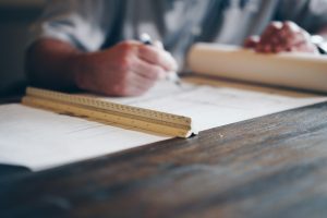 Mains traçant un plan avec une règle, à l'image du cadrage d'une application métier sur mesure