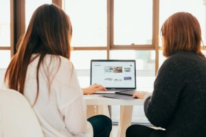 Deux collègues échangeant devant un ordinateur portable, illustrant l'accompagnement à la mise en place d'Odoo MCP
